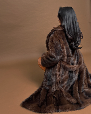 Person wearing a brown fur coat against a brown background